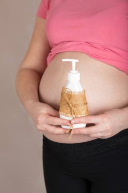 Genç hamile kadın samimi jel plastik şişe tutar. 