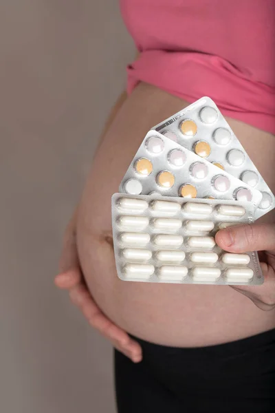 Junge Schwangere hält Tablettenfilme dicht am Bauch. Stockbild