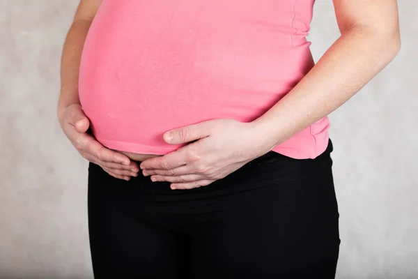 Молодая беременная женщина держит руки на животе . — стоковое фото