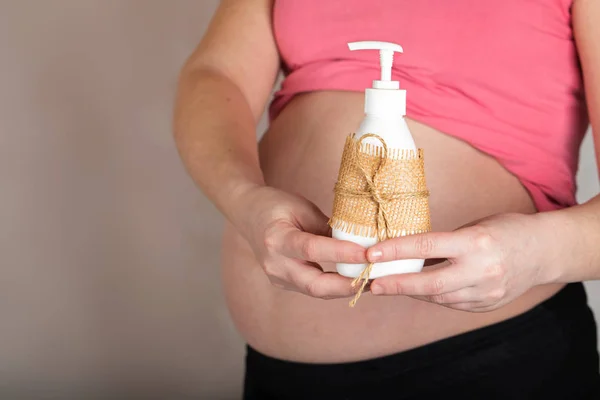 Молодая беременная женщина держит пластиковую бутылку интимного геля . — стоковое фото