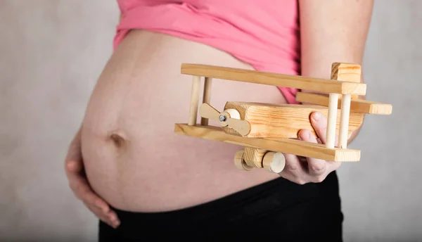 Молодая беременная женщина держит деревянный самолет . — стоковое фото