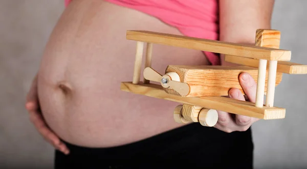 Молодая беременная женщина держит деревянный самолет . — стоковое фото