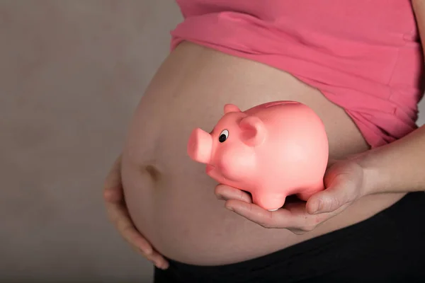 Jovem grávida mulher mantém rosa porquinho banco . — Fotografia de Stock