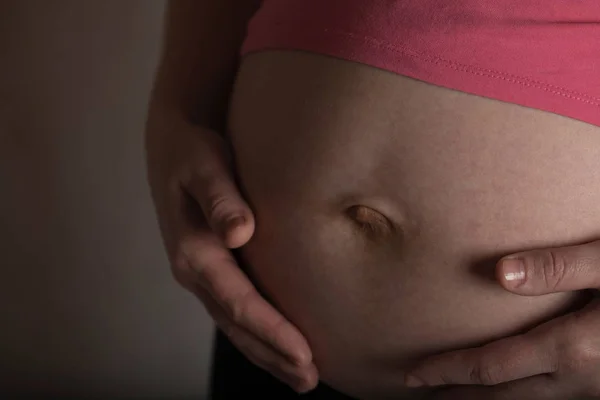 La joven embarazada toca su vientre. Luz dramática . — Foto de Stock