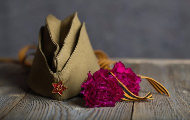 Askeri şapka, karanfiller, ahşap bir surfac üzerinde Saint George şerit