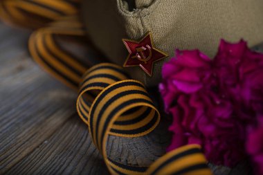 Askeri şapka, karanfiller, ahşap bir surfac üzerinde Saint George şerit