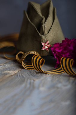 Askeri şapka, karanfiller, ahşap bir surfac üzerinde Saint George şerit
