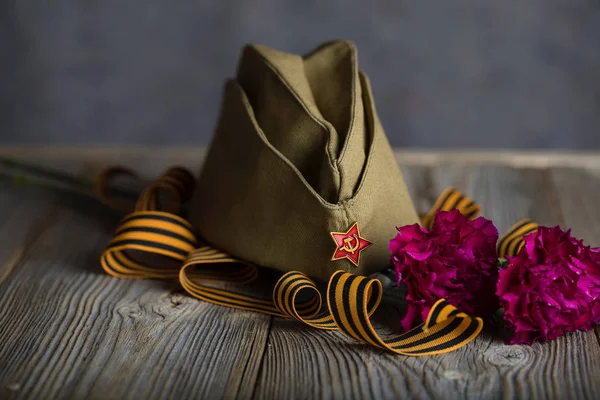 军帽，康乃馨，圣乔治丝带在木制冲浪 — 图库照片