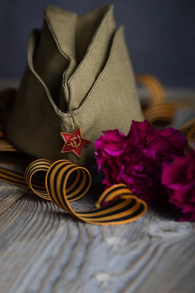 Gorra militar, claveles, cinta de San Jorge sobre un surfac de madera —  Fotos de Stock