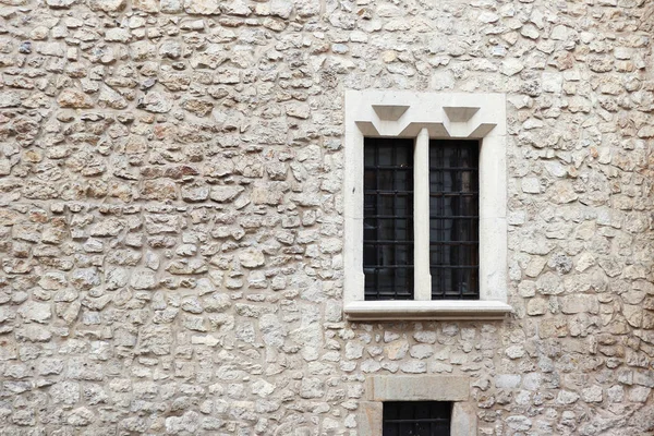 Old stone wall and cement with old window. Stone background. Krakow stone wall. Griddles on the windows. Krakow building