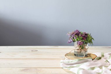 İki bardak, su bir kase, havlu, bahar çiçekleri ahşap masa üzerinde. Güneşli sabah. Kahvaltı. 