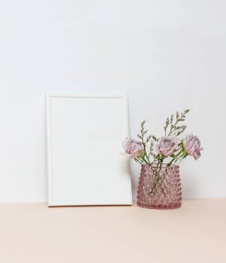 Masanın üstüne üç pembe Güllü beyaz çerçeve