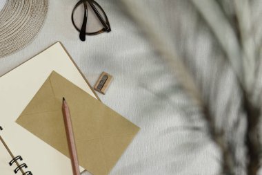 Açık defter, kalem, kalemtıraş, zarf, Gözlük, şapka masa ve gölge