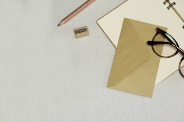 Açılan dizüstü bilgisayar, kalem, kalemtıraş, zarf, beyaz arka planda gözlükler