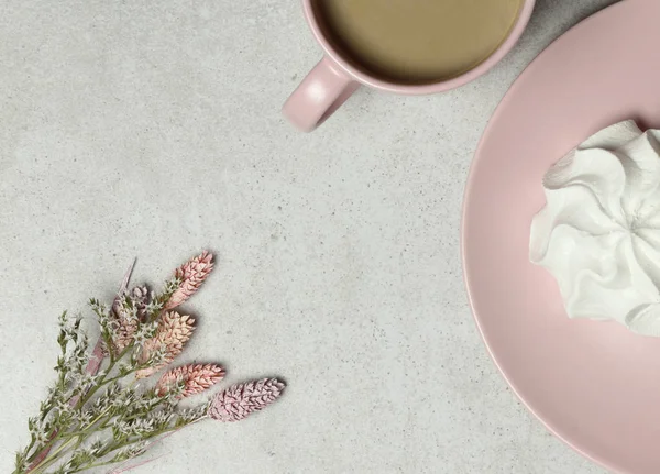 The pink cup of coffee, marshmallow, bouquet of white flowers on the granite texture