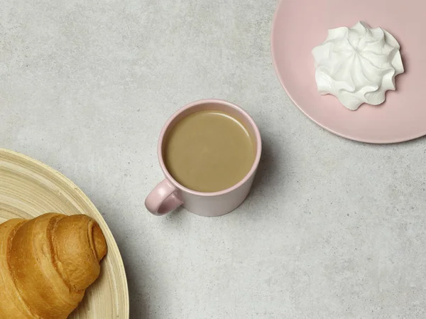 The pink cup of cappuccino with marshmallow and croissant on the granite background
