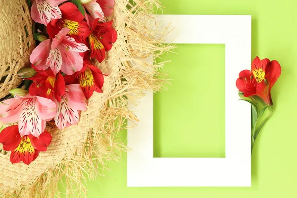 Summer flat lay mockup frame With straw hat decorated tropical flowers on green background