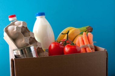 Yemek servisi. Marketli karton kutu. Domates, muz, süt, karton kutuda yumurta, havuç, konserve yağ şişesi