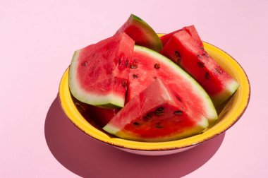 Pembe arka planda sarı Bolca dilimlenmiş taze karpuz. Uzayı metin için kopyala. Yaz meyvesi.