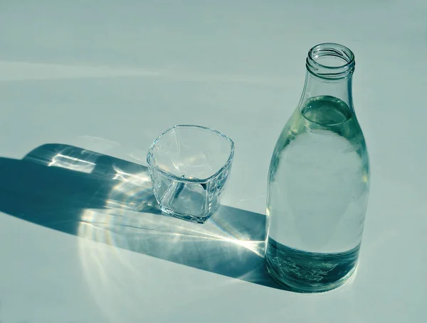 transparent glass, vintage glass bottle of water on a white background with a sunbeam, close up