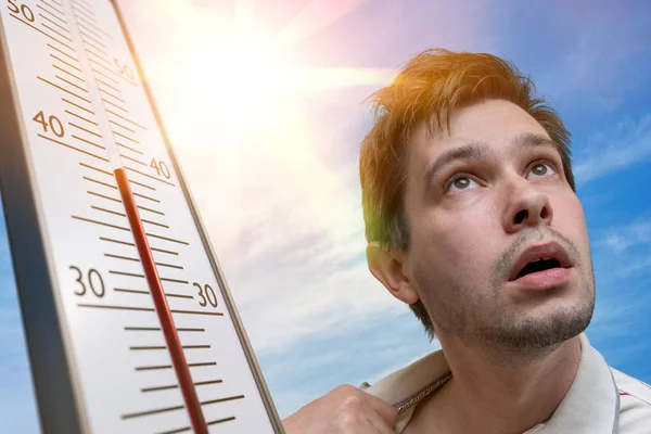 炎热的天气概念 年轻人出汗了 温度计呈高温 背景太阳 — 图库照片