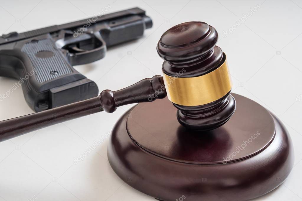 Gavel in front of a pistol. Gun laws and legislation concept.