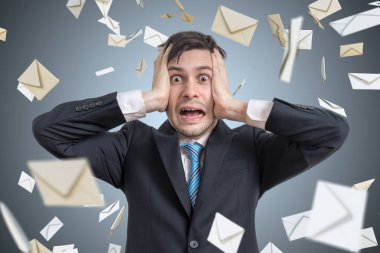 Hayal kırıklığına uğramış genç adam ve birçok düşen zarflar. Birçok e-posta ve spam kavramı.