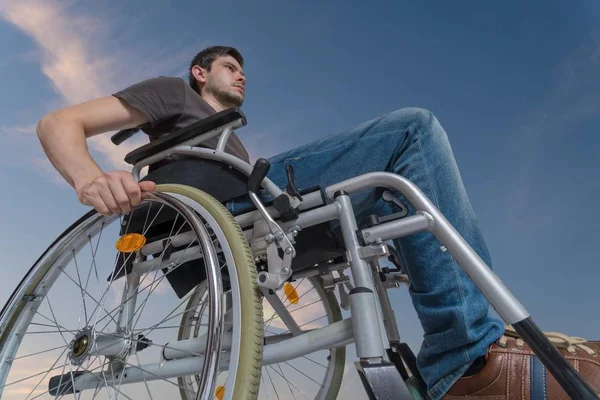 Niepełnosprawny człowiek jest siedzący na wózku inwalidzkim. Niebo w ekspresyjne — Zdjęcie stockowe