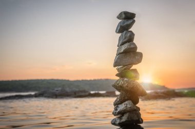 Zen dengeli taşlar gün batımında deniz kıyısında yığılmış. Denge ve 