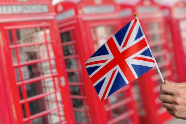 Büyük Britanya bayrağı ve arka planda birçok Londra kırmızı telefon kulübesi.