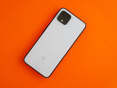 Uk, Ekim 2019: Renkli turuncu arka plan masasında piksel4 beyaz akıllı telefon