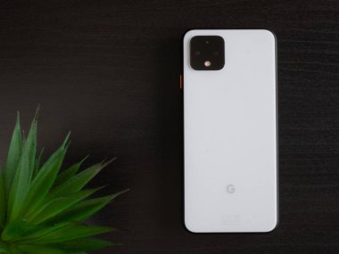 Uk, Ekim 2019: Piksel 4 beyaz akıllı telefon koyu ahşap ofis masasında bitki ile