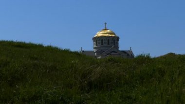 Tepenin arkasından bakmak Christian kilisenin kubbesi. Kilisenin altın kubbesi mavi gökyüzüne karşı çim görülür.
