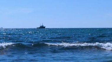 Yavaş yavaş ufukta hareketli deniz çekici. Bir motorlu tekne ve mavi gökyüzü ile hafif deniz meltemi.