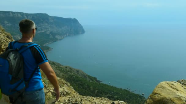 Человек Солнечных Очках Рюкзаком Стоящим Высоко Горе Над Морем Против — стоковое видео