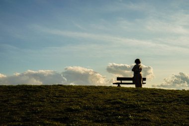 Günbatımının tepelerinde oturan kadın silueti