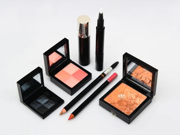 Cosmetic sets with eye shadows and brushes in black plastic cases with mirror on white background