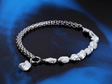 Şatafatlı, zarif, mavi arka planda kolyesi olan bir inci kolye. Yakın çekim. 