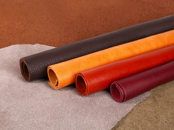 Rolled up different colors natural leather textures samples on leather background