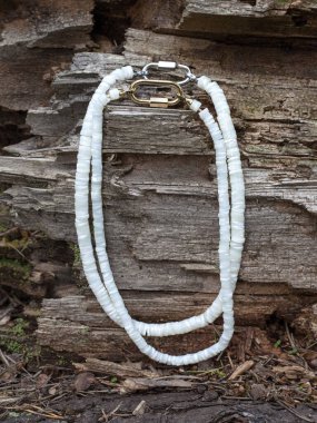 Doğal ahşap arka plandaki kadına hediye olarak cilalanmış parçalardan elde yapılmış inci kolyeler.