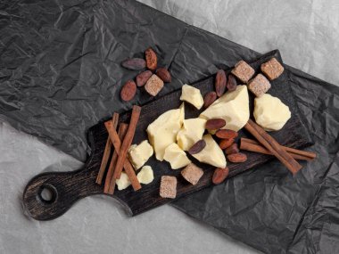 Tarçınlı kakao yağı, kakao çekirdeği ve siyah ve gri arka planda kamış şekeri parçaları. Kopyalama alanı olan üst görünüm