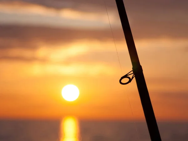 海水釣り 明るい日没の背景に釣竿 回転棒 — ストック写真