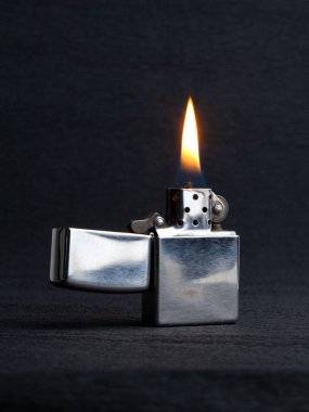 Close-up of metal gas lighter with burning fire on grey background with copy space clipart