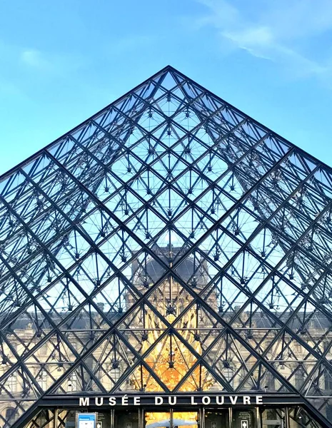 PARÍS, FRANCIA - 25 DE MAYO DE 2015: Famosa Pirámide del Museo del Louvre de vidrio con reflejos de cielo azul y nubes —  Fotos de Stock