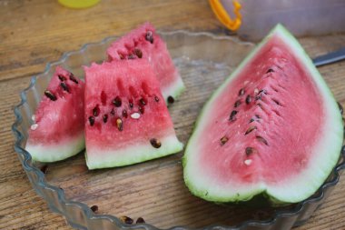 Olgun karpuz, dilimler halinde dilimlenmiş ve açık güneşli bir günde yakın plan çekimde masada uzanmış. Arkaplan ya da duvar kağıdı olarak ve diğer tasarım fikirlerinizde kullanılabilir.