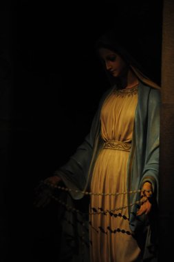 Commovente statua di Madonna illuminata da una calda luce, Vince le tenebre