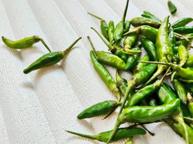 Bir yığın taze, küçük yeşil kırmızı biber ışığa karşı, dokulu arka plan, onların ateşli doğasını yakalıyor..