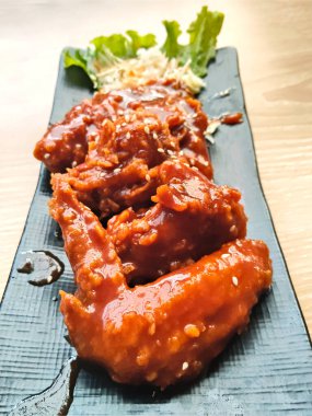 Yakın plan kızarmış tavuk kanadı kalın, baharatlı kırmızı sosla kaplanmış ve susam tohumlarıyla kaplanmış..