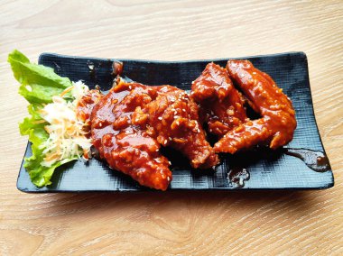 Yakın plan kızarmış tavuk kanadı kalın, baharatlı kırmızı sosla kaplanmış ve susam tohumlarıyla kaplanmış..