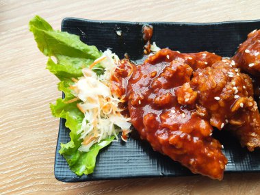 Yakın plan kızarmış tavuk kanadı kalın, baharatlı kırmızı sosla kaplanmış ve susam tohumlarıyla kaplanmış..